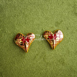 This is a pair of heart earrings with puzzle blocks pattern on the surface. The earrings feature a vibrant enamel center that mimics a beating heart flowing with love. The material of the earrings is sterling silver and enamel, and the color is vintage gold color
