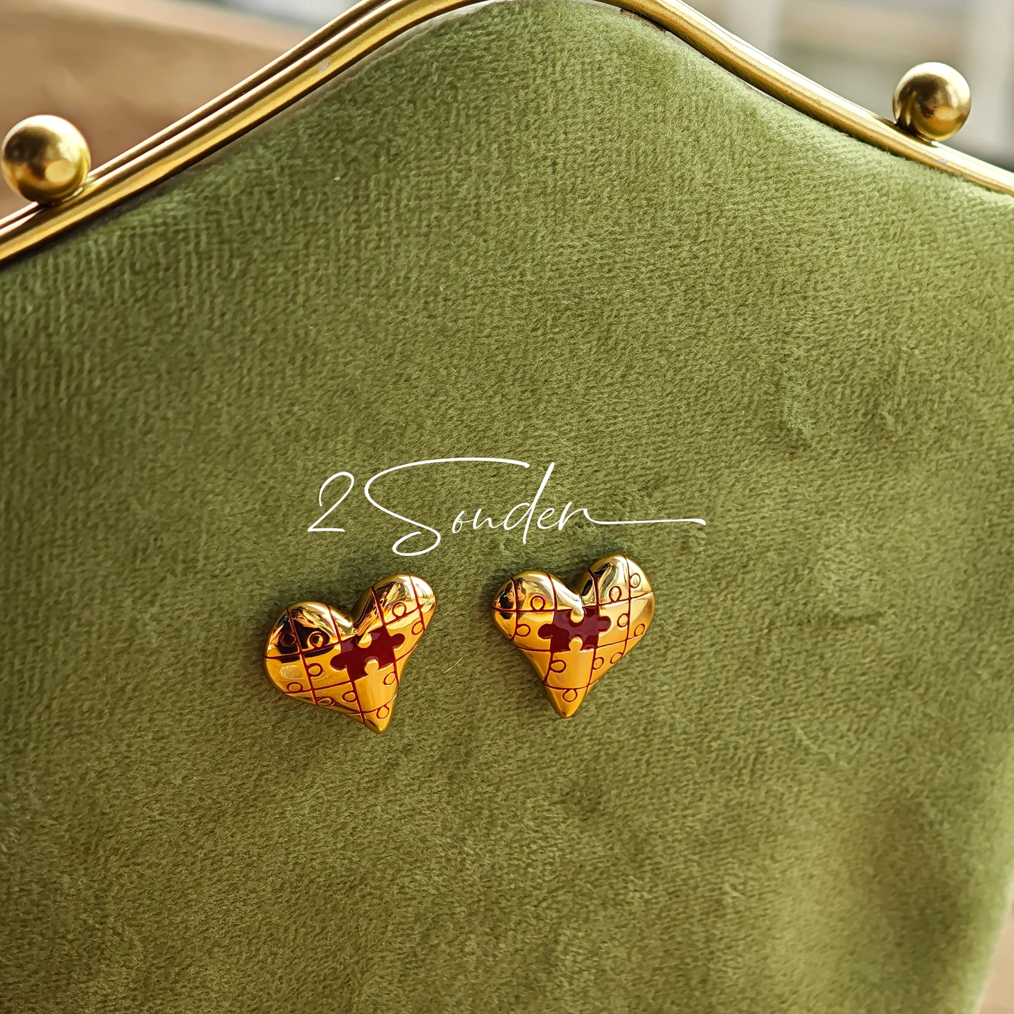 This is a pair of heart earrings with puzzle blocks pattern on the surface. The earrings feature a vibrant enamel center that mimics a beating heart flowing with love. The material of the earrings is sterling silver and enamel, and the color is vintage gold color