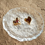 This is a pair of heart earrings with puzzle blocks pattern on the surface. The earrings feature a vibrant enamel center that mimics a beating heart flowing with love. The material of the earrings is sterling silver and enamel, and the color is vintage gold color