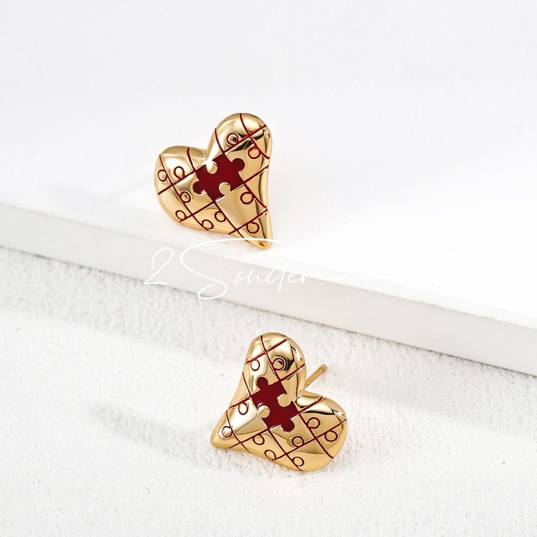 This is a pair of heart earrings with puzzle blocks pattern on the surface. The earrings feature a vibrant enamel center that mimics a beating heart flowing with love. The material of the earrings is sterling silver and enamel, and the color is vintage gold color