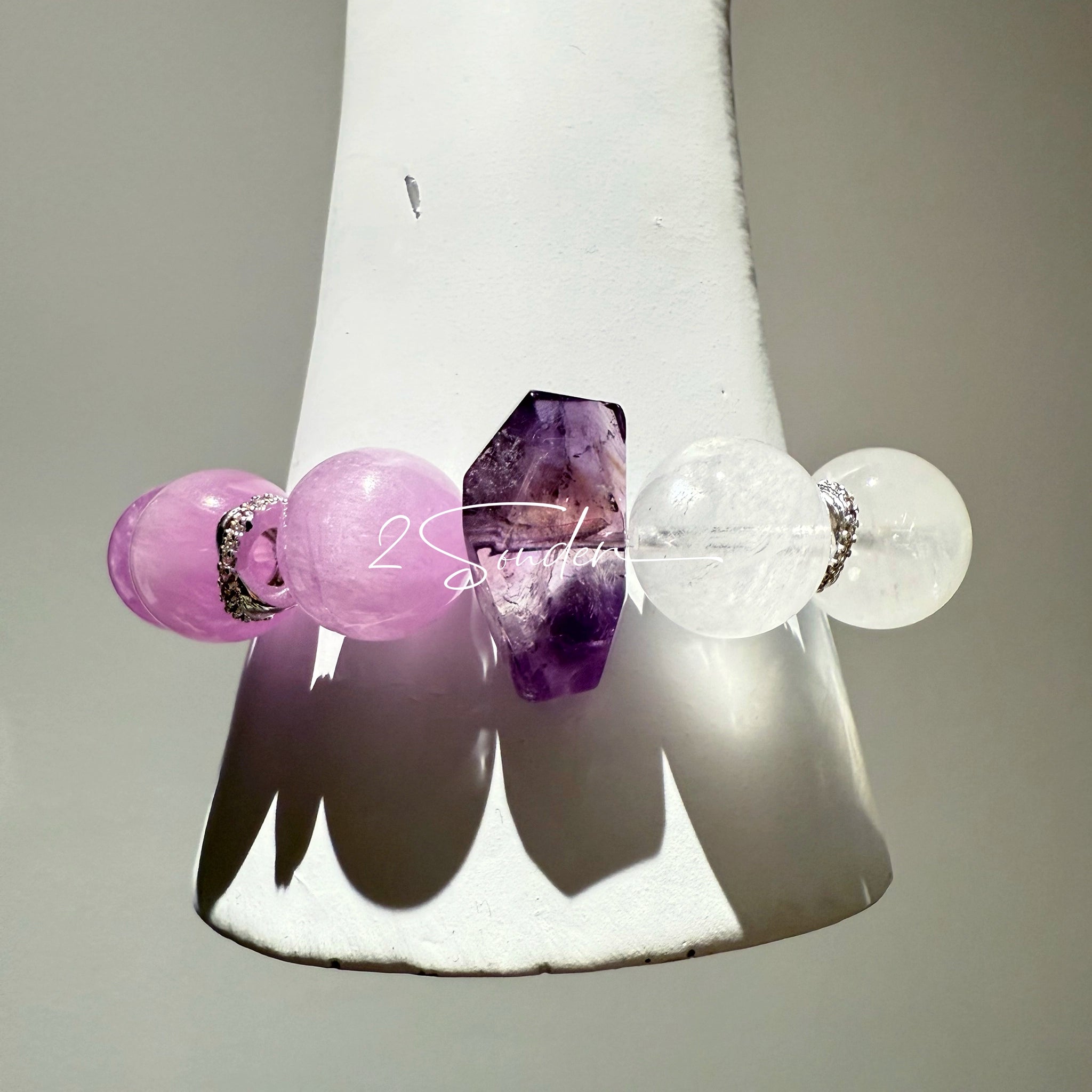 This is a multi gemstones bracelet consists of Kunzite, White Phantom Quartzs and Raw Amethysts. The beads are between 14.5 and 15.5mm. And in the bracelets, there are  hypoallergenic silver spacers and floral accents.