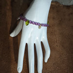 A purple hand-strung bracelet with luminous Czech glass beads & delicate botanical charms.