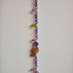 A purple hand-strung bracelet with luminous Czech glass beads & delicate botanical charms.