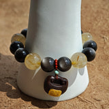 A regal strand of silver-obsidian shields and golden rutile sunbursts, anchored by fragrant agarwood and crimson Nanhong agate.