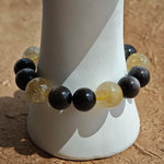 Gleaming silver obsidian spheres meet radiant golden rutile beads, then sink into the earthy warmth of agarwood and fiery Nanhong agate.