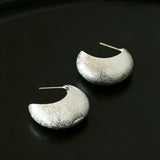 These minimalist high-end stud earrings feature a plump crescent C-shaped design with delicate frosted texture on the whole surface. They are available in two classic colors: elegant gold and versatile silver. With smooth curved lines, the earrings bring understated luxury and fashionable daily wear sense.