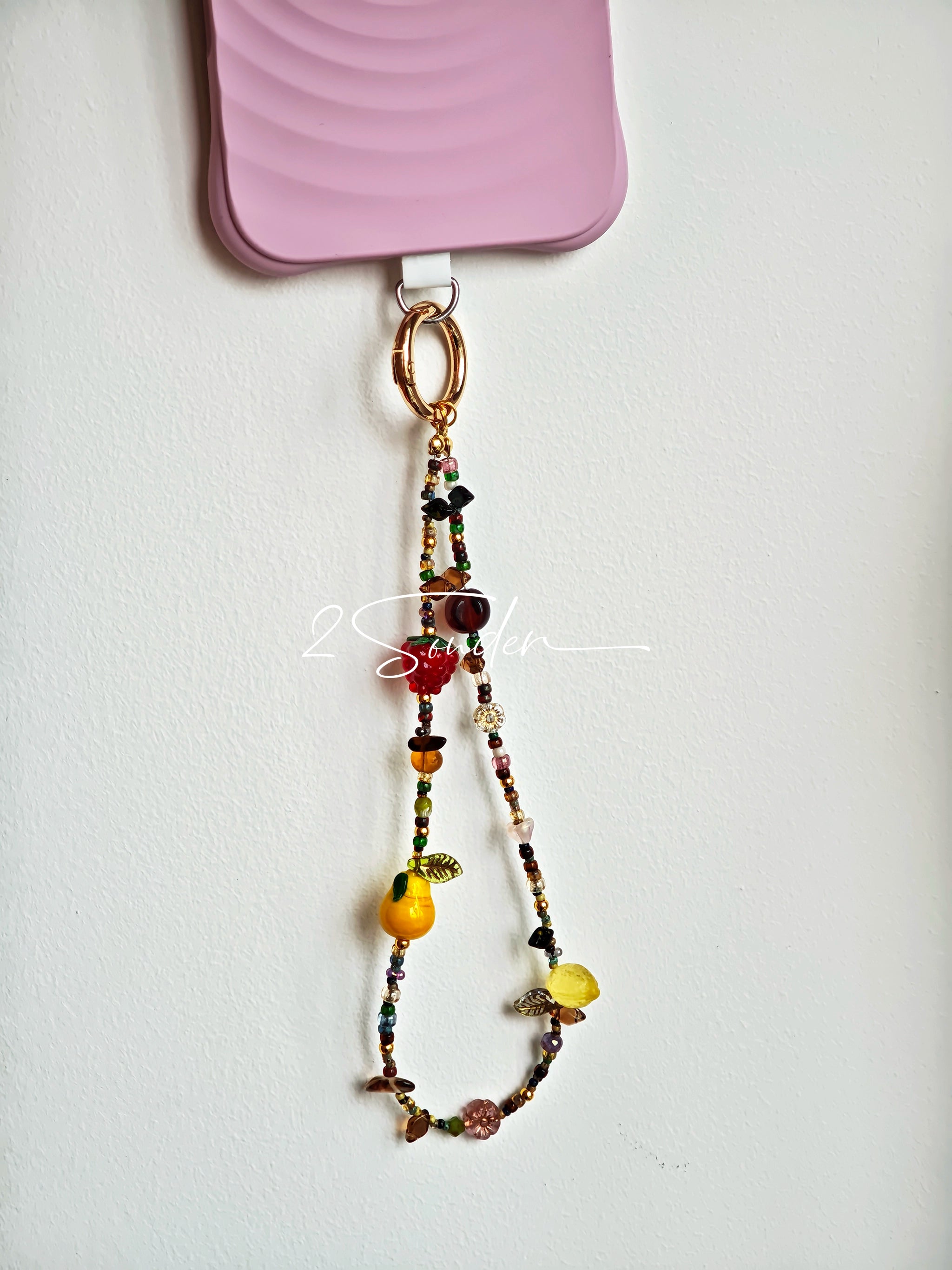 This handmade Czech glass bead bag charm is also perfect as a phone strap, keychain accessory, or a car decor. Featuring translucent beads, fruity spacers (pear, lemon, strawberry!), whimsical floral leaves and durable gold-tone hardware, it’s like wearing a garden on your keys.