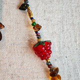 This handmade Czech glass bead bag charm is also perfect as a phone strap, keychain accessory, or a car decor. Featuring translucent beads, fruity spacers (pear, lemon, strawberry!), whimsical floral leaves and durable gold-tone hardware, it’s like wearing a garden on your keys.