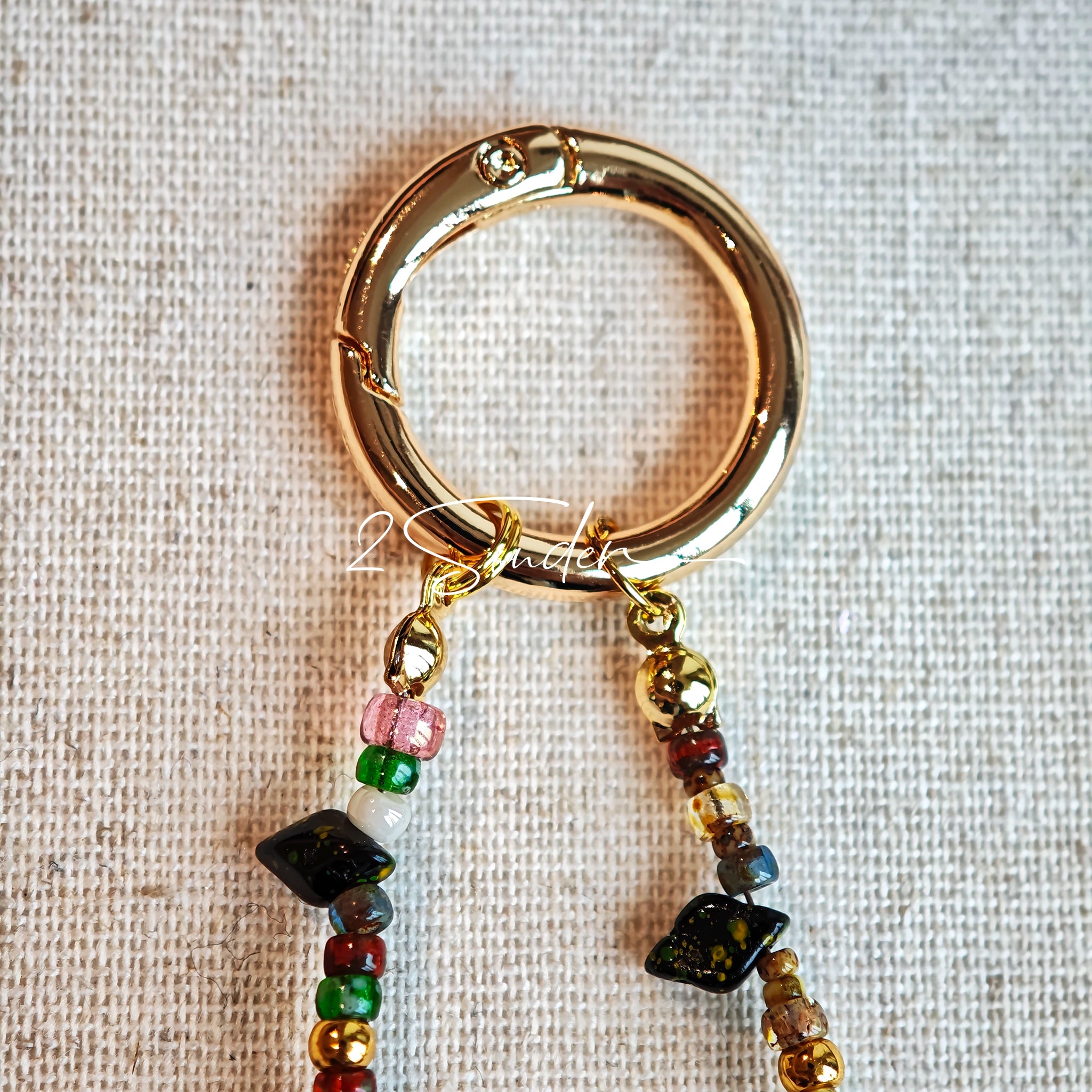 This handmade Czech glass bead bag charm is also perfect as a phone strap, keychain accessory, or a car decor. Featuring translucent beads, fruity spacers (pear, lemon, strawberry!), whimsical floral leaves and durable gold-tone hardware, it’s like wearing a garden on your keys.