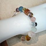 This stunning multi-gem crystal bracelet is a vibrant rainbow of natural stones, featuring smooth round beads in hues of clear, amethyst, sky blue, soft pink, golden, and smoky brown, interspersed with striking square and geometric-cut accents.
Each bead showcases unique inclusions: delicate black rutile in the gray square, fiery red hair-like strands in the brown square, and subtle mineral veining throughout, creating a one-of-a-kind, textured masterpiece.
The eclectic mix of gemstones—from amethyst and ro
