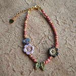 Vibrant pink Czech glass beads are highlighted by blue, purple, and black flower charms and green leaf accents, creating a stunningly attractive design.