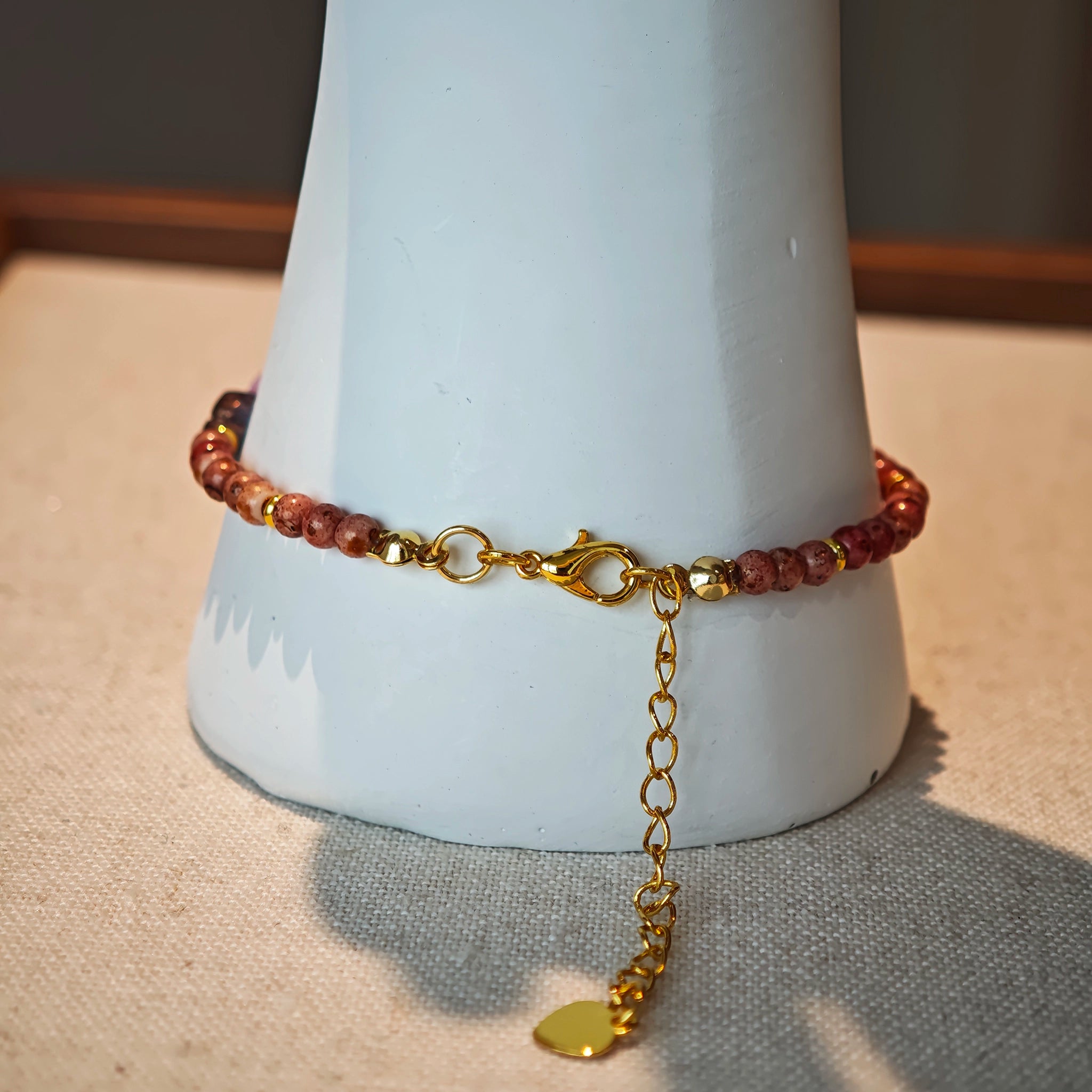 Vibrant pink Czech glass beads are highlighted by blue, purple, and black flower charms and green leaf accents, creating a stunningly attractive design.