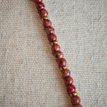 Vibrant pink Czech glass beads are highlighted by blue, purple, and black flower charms and green leaf accents, creating a stunningly attractive design.