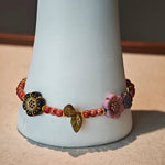 Vibrant pink Czech glass beads are highlighted by blue, purple, and black flower charms and green leaf accents, creating a stunningly attractive design.