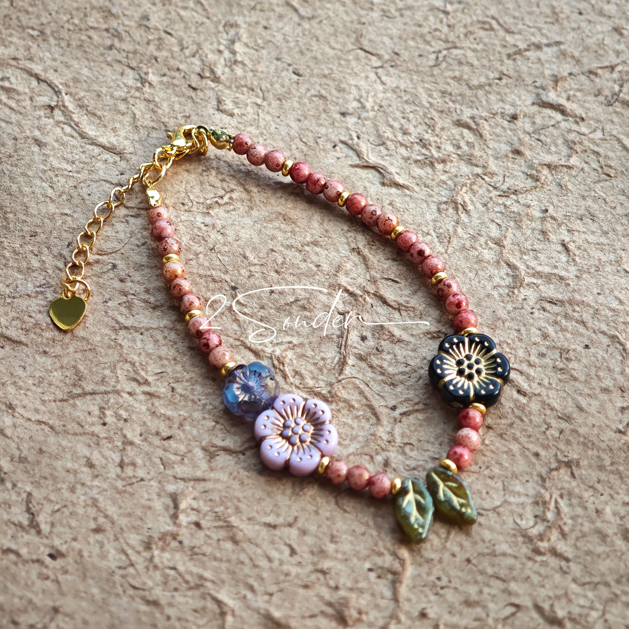 This is a bracelet that made of Czech beads. And it's highlighted by blue, purple, and black flower charms and green leaf accents, creating a stunningly attractive design.