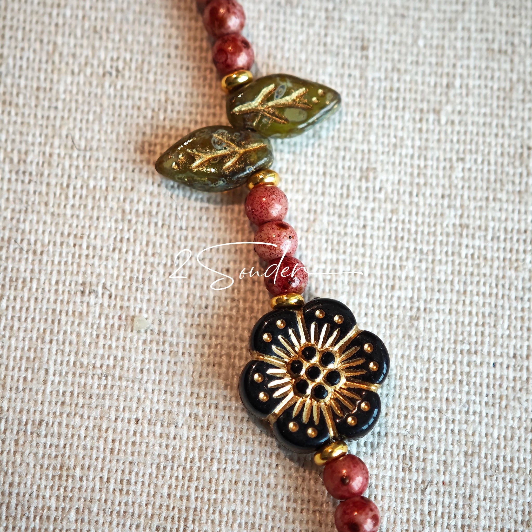 This is a bracelet that made of Czech beads. And it's highlighted by blue, purple, and black flower charms and green leaf accents, creating a stunningly attractive design.