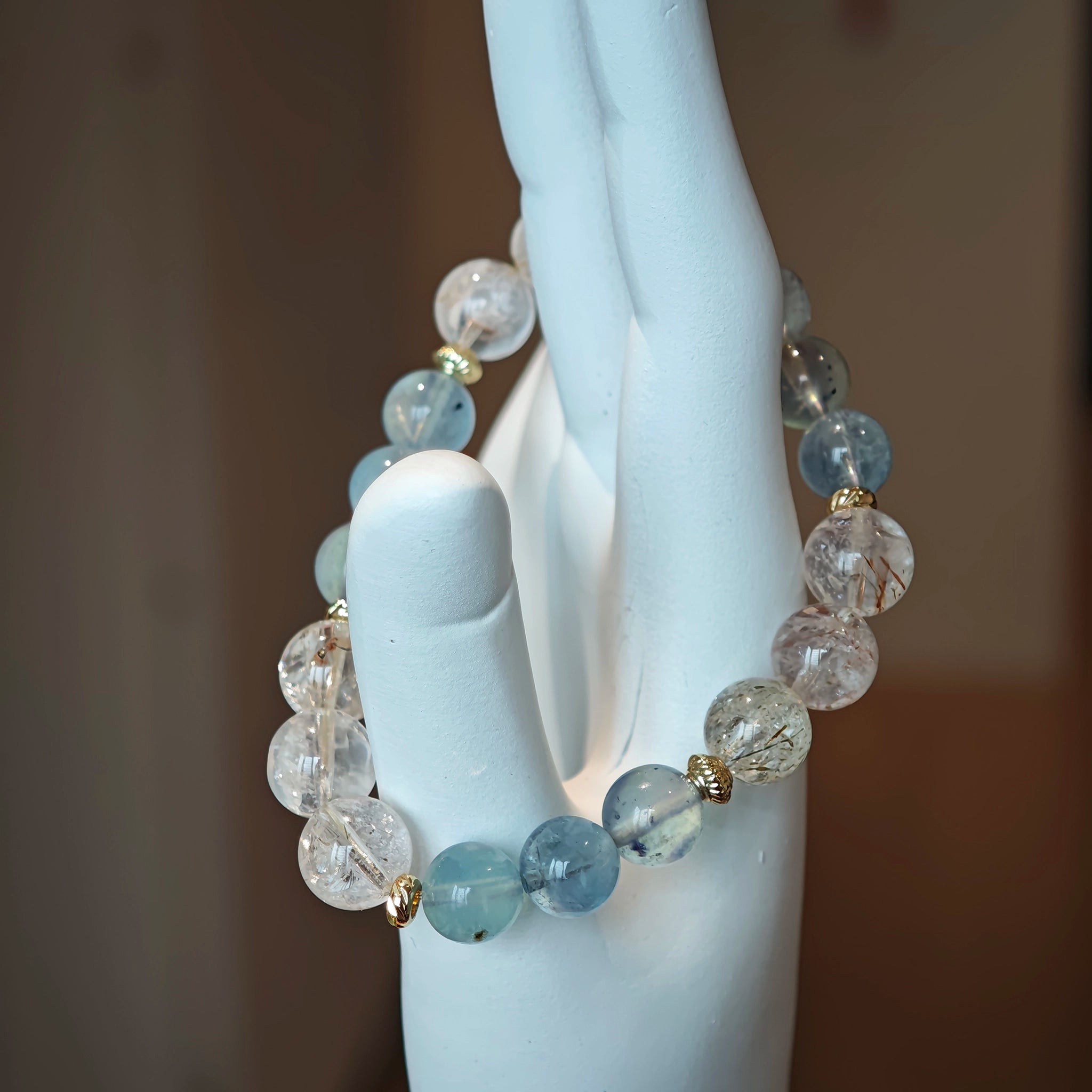 Cool waves of aqua roll beside golden rutile threads, tied with polished gold.
