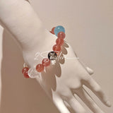 This bracelet is centered around a prominent round light blue aquamarine bead, surrounded by rich reddish-brown strawberry quartz beads. It is accented with clear crystal, black rutilated quartz, and golden rutilated quartz beads, along with delicate gold spacers, creating a harmonious natural stone design.