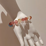 This bracelet is centered around a prominent round light blue aquamarine bead, surrounded by rich reddish-brown strawberry quartz beads. It is accented with clear crystal, black rutilated quartz, and golden rutilated quartz beads, along with delicate gold spacers, creating a harmonious natural stone design.