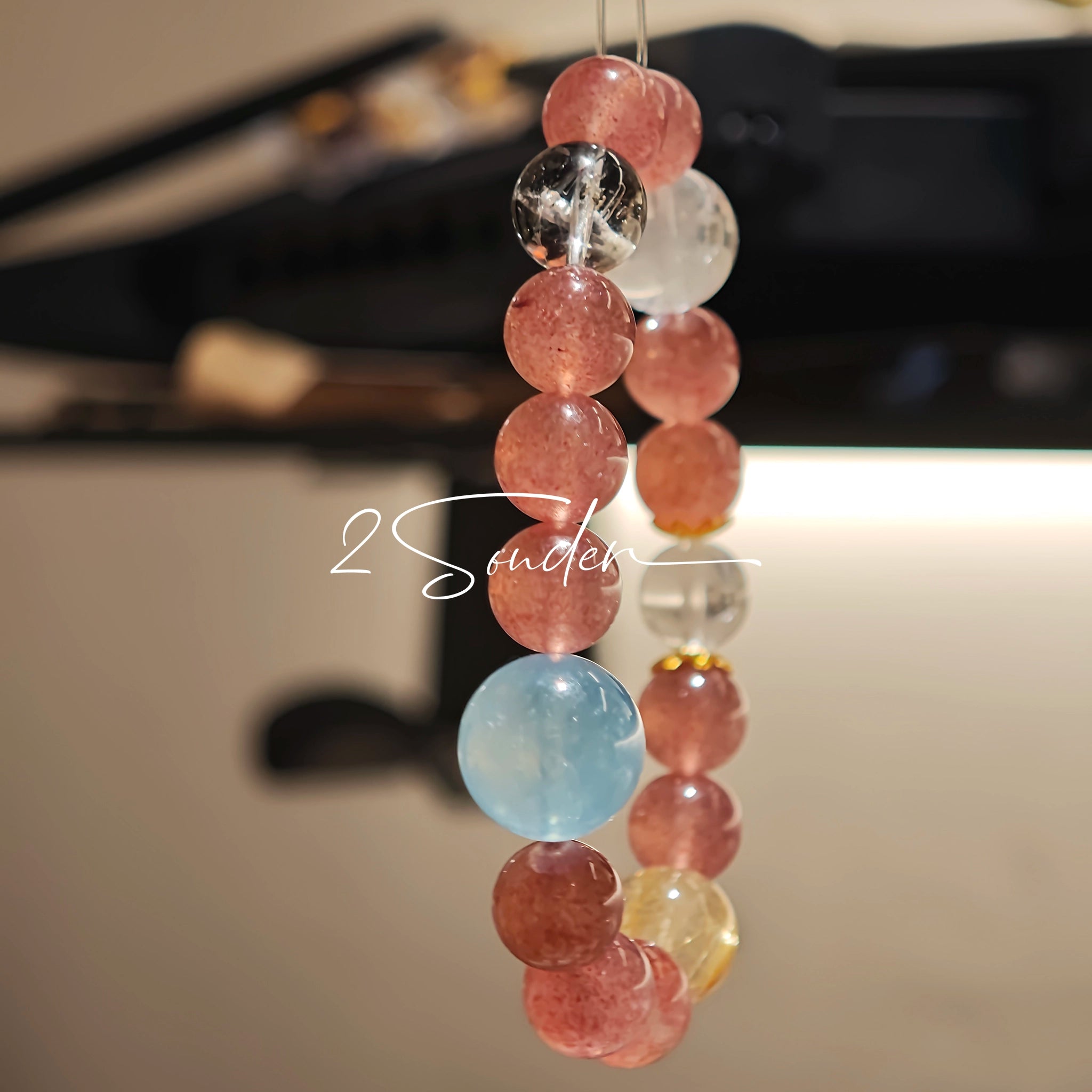 This bracelet is centered around a prominent round light blue aquamarine bead, surrounded by rich reddish-brown strawberry quartz beads. It is accented with clear crystal, black rutilated quartz, and golden rutilated quartz beads, along with delicate gold spacers, creating a harmonious natural stone design.