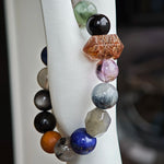 Wrapped in smoky indigo, the bracelet gathers Black Gold Super Seven, Herkimer diamonds, clear quartz, sandalwood, amethyst, silver obsidian, white phantom, and kyanite.