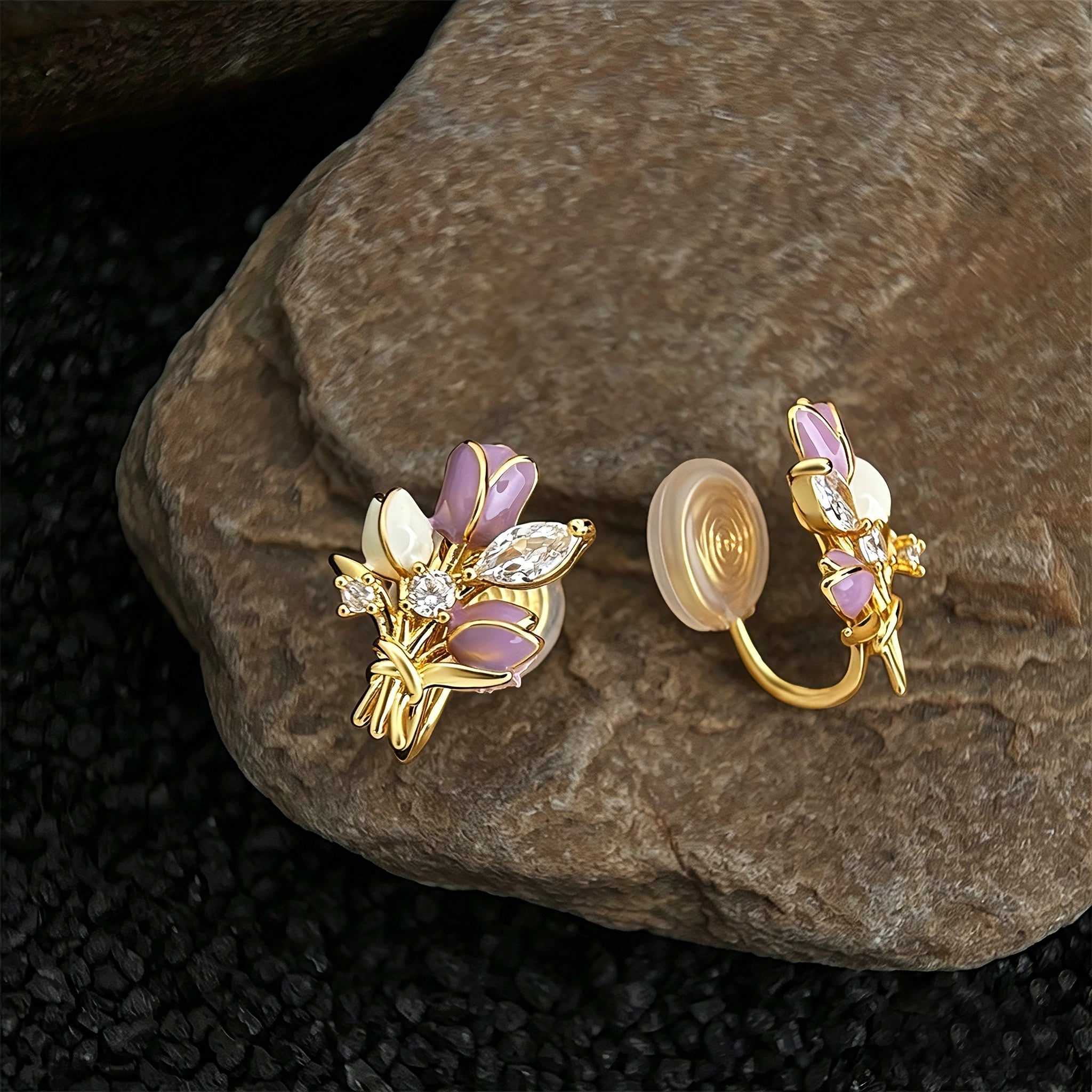 These stud earrings feature an elegant bouquet design, crafted with a thick 18K real gold plating. The arrangement showcases delicate purple and white enamel tulip flowers, accented with sparkling marquise and round-cut cubic zirconia stones, all set in a polished gold-tone metal structure tied with a decorative knot at the base. The overall style is romantic and refined, perfect for adding a touch of floral charm to any look.
