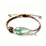 This hand-woven bracelet features a delicate translucent jade fish charm, symbolizing good fortune and abundance. Its vibrant multi-colored braided cord blends retro aesthetics with playful dopamine styling, finished with adjustable knots for a comfortable fit.