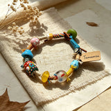 This handmade boho bracelet bursts with vibrant dopamine colors, featuring hand-painted clay beads, twisted linen threads, and quirky sculpted charms. Every bead and wrapped fiber is carefully crafted, bringing playful, retro artistic vibes to your wrist. It is a unique wearable art piece full of whimsical details.