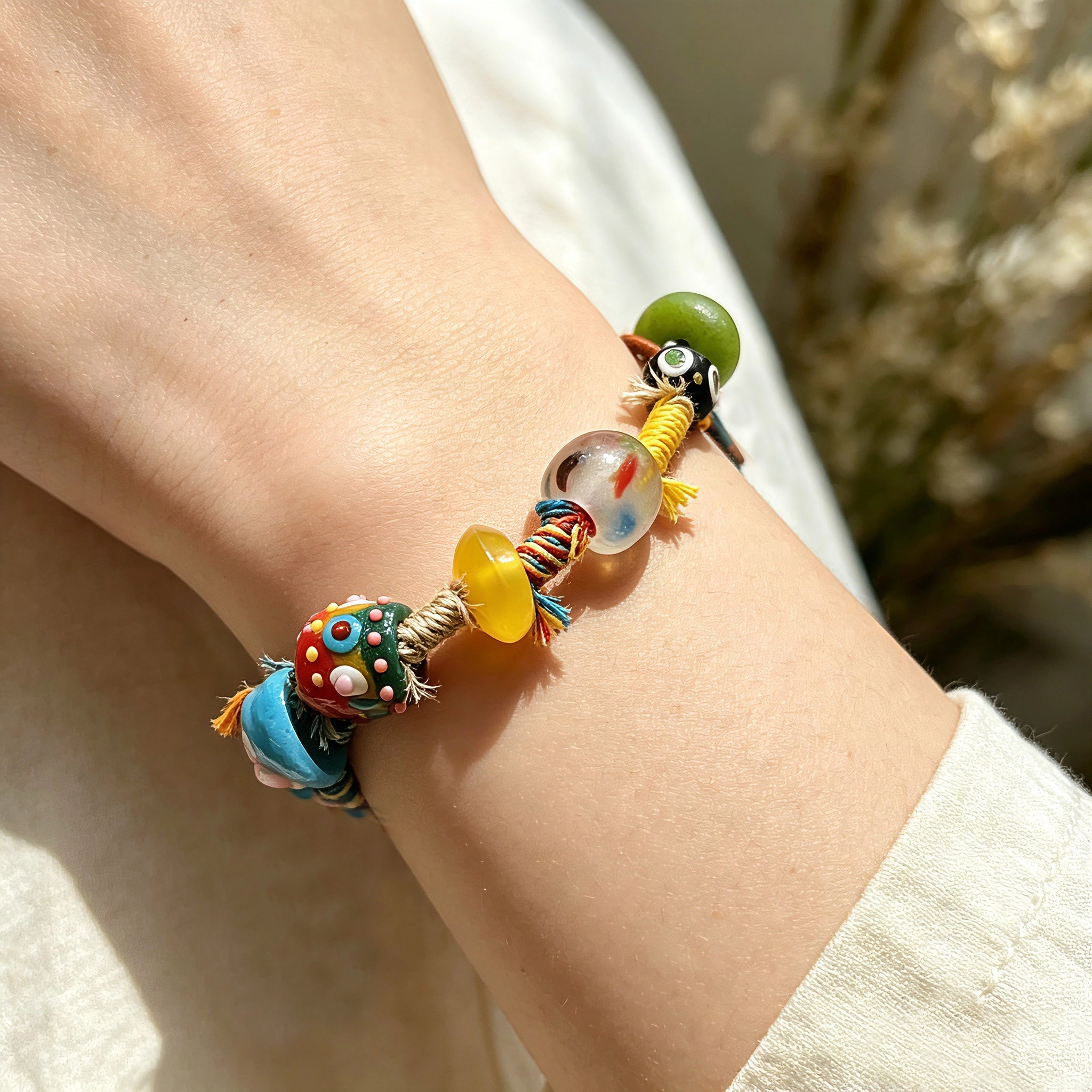 This handmade boho bracelet bursts with vibrant dopamine colors, featuring hand-painted clay beads, twisted linen threads, and quirky sculpted charms. Every bead and wrapped fiber is carefully crafted, bringing playful, retro artistic vibes to your wrist. It is a unique wearable art piece full of whimsical details.