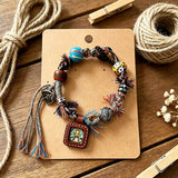This vintage hand-woven bracelet features vibrant mixed-color tassels and diverse decorative beads. It comes with a small leather thangka pendant, blending ethnic charm with playful dopamine styling. Each braided detail is handcrafted for a unique, bohemian look.