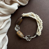 This handcrafted vintage bracelet blends creamy pale beads, textured wooden cylinders and faceted clear quartz for an earthy, bohemian look. Detailed antique silver accents add subtle depth, making it a unique layered accessory full of natural charm.