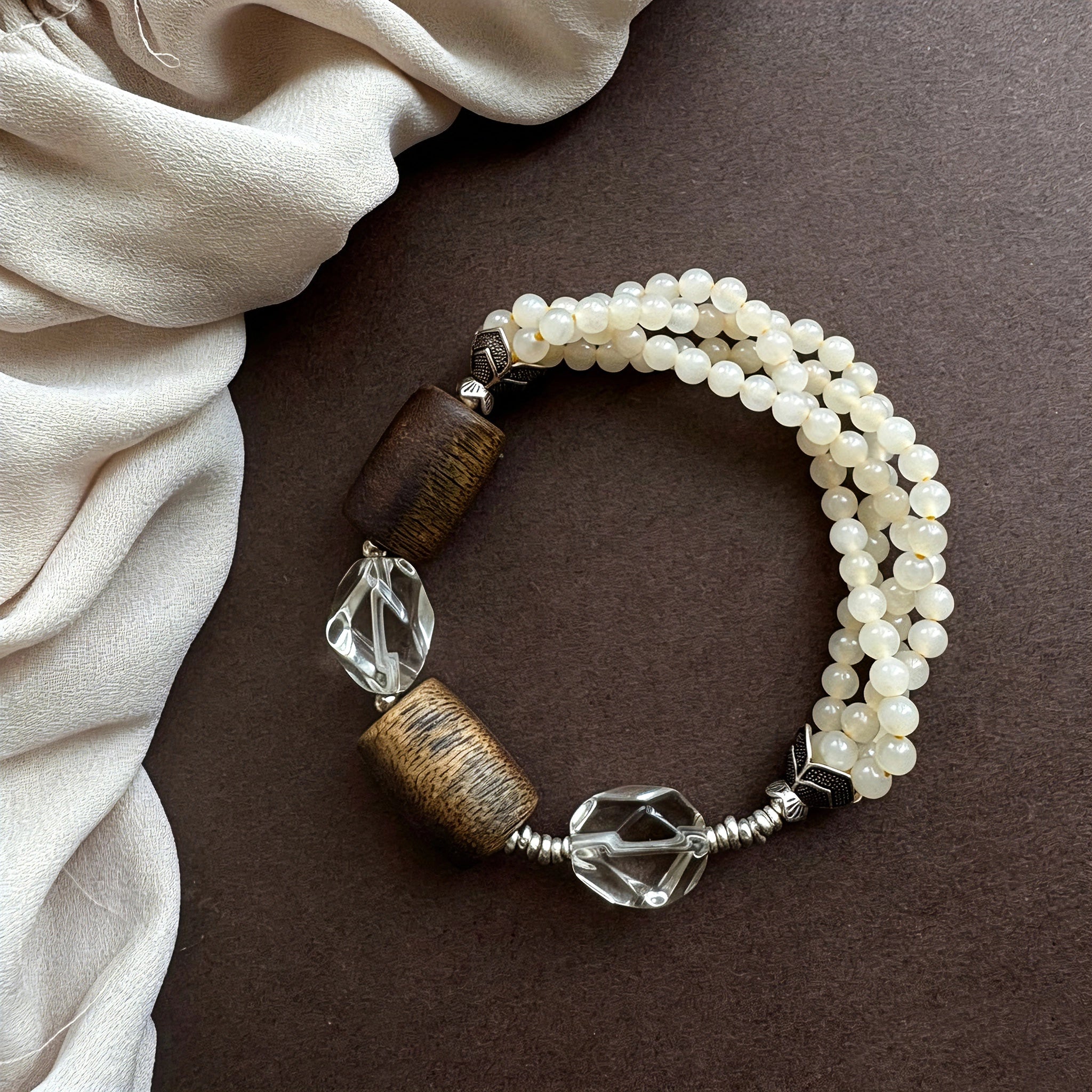 This handcrafted vintage bracelet blends creamy pale beads, textured wooden cylinders and faceted clear quartz for an earthy, bohemian look. Detailed antique silver accents add subtle depth, making it a unique layered accessory full of natural charm.