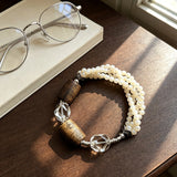 This handcrafted vintage bracelet blends creamy pale beads, textured wooden cylinders and faceted clear quartz for an earthy, bohemian look. Detailed antique silver accents add subtle depth, making it a unique layered accessory full of natural charm.