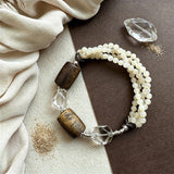 This handcrafted vintage bracelet blends creamy pale beads, textured wooden cylinders and faceted clear quartz for an earthy, bohemian look. Detailed antique silver accents add subtle depth, making it a unique layered accessory full of natural charm.