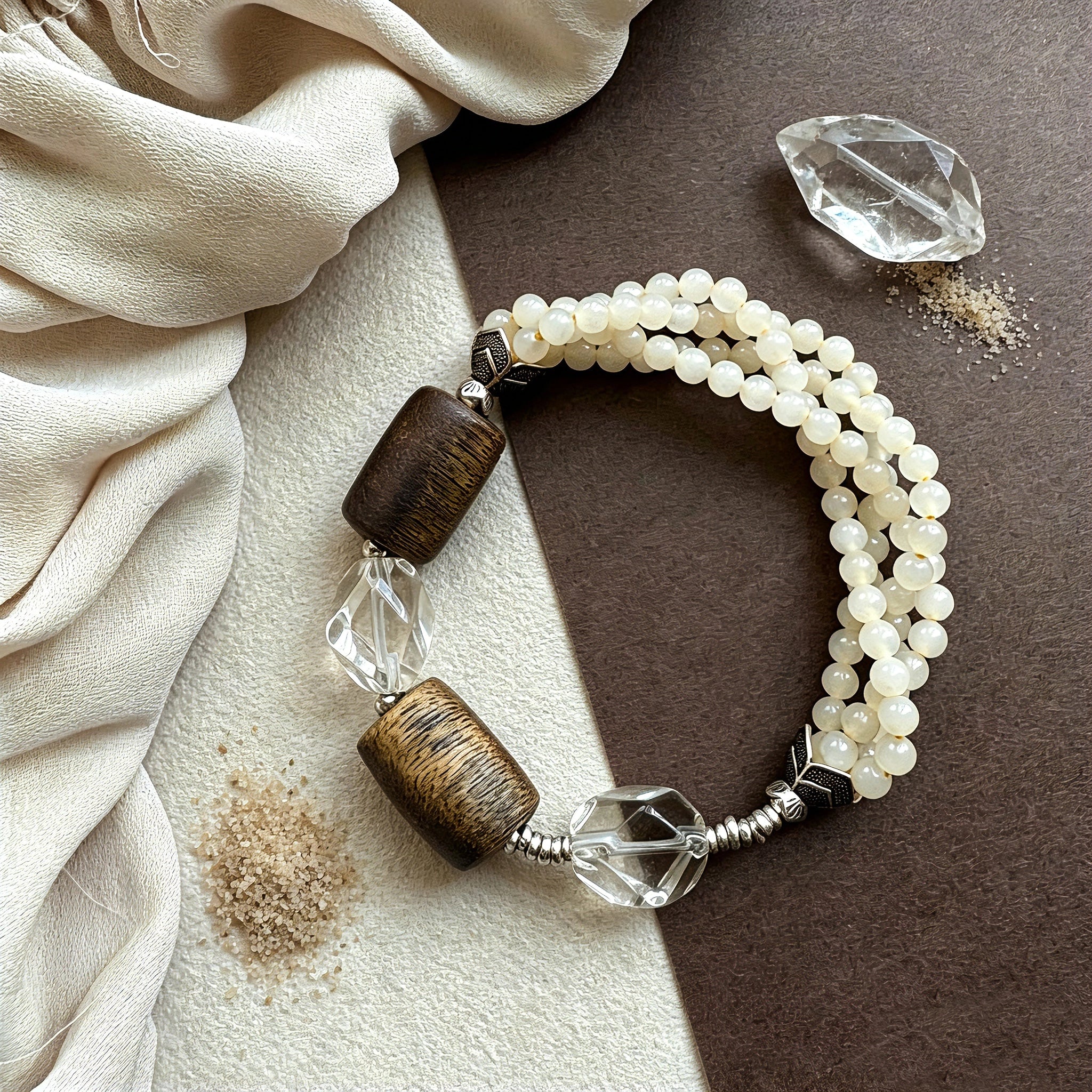 This handcrafted vintage bracelet blends creamy pale beads, textured wooden cylinders and faceted clear quartz for an earthy, bohemian look. Detailed antique silver accents add subtle depth, making it a unique layered accessory full of natural charm.