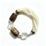 This handcrafted vintage bracelet blends creamy pale beads, textured wooden cylinders and faceted clear quartz for an earthy, bohemian look. Detailed antique silver accents add subtle depth, making it a unique layered accessory full of natural charm.