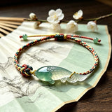 This hand-woven bracelet features a delicate translucent jade fish charm, symbolizing good fortune and abundance. Its vibrant multi-colored braided cord blends retro aesthetics with playful dopamine styling, finished with adjustable knots for a comfortable fit.