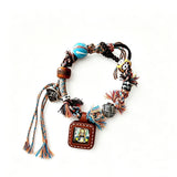 This vintage hand-woven bracelet features vibrant mixed-color tassels and diverse decorative beads. It comes with a small leather thangka pendant, blending ethnic charm with playful dopamine styling. Each braided detail is handcrafted for a unique, bohemian look.