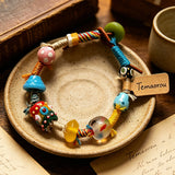 This handmade boho bracelet bursts with vibrant dopamine colors, featuring hand-painted clay beads, twisted linen threads, and quirky sculpted charms. Every bead and wrapped fiber is carefully crafted, bringing playful, retro artistic vibes to your wrist. It is a unique wearable art piece full of whimsical details.
