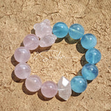 This bracelet consists of rose quartz and aquamarine. The bracelet features a bead pendant and a rhombic spacer, both of which are made of rose quartz. The bracelet is a combination of pink and blue colors.