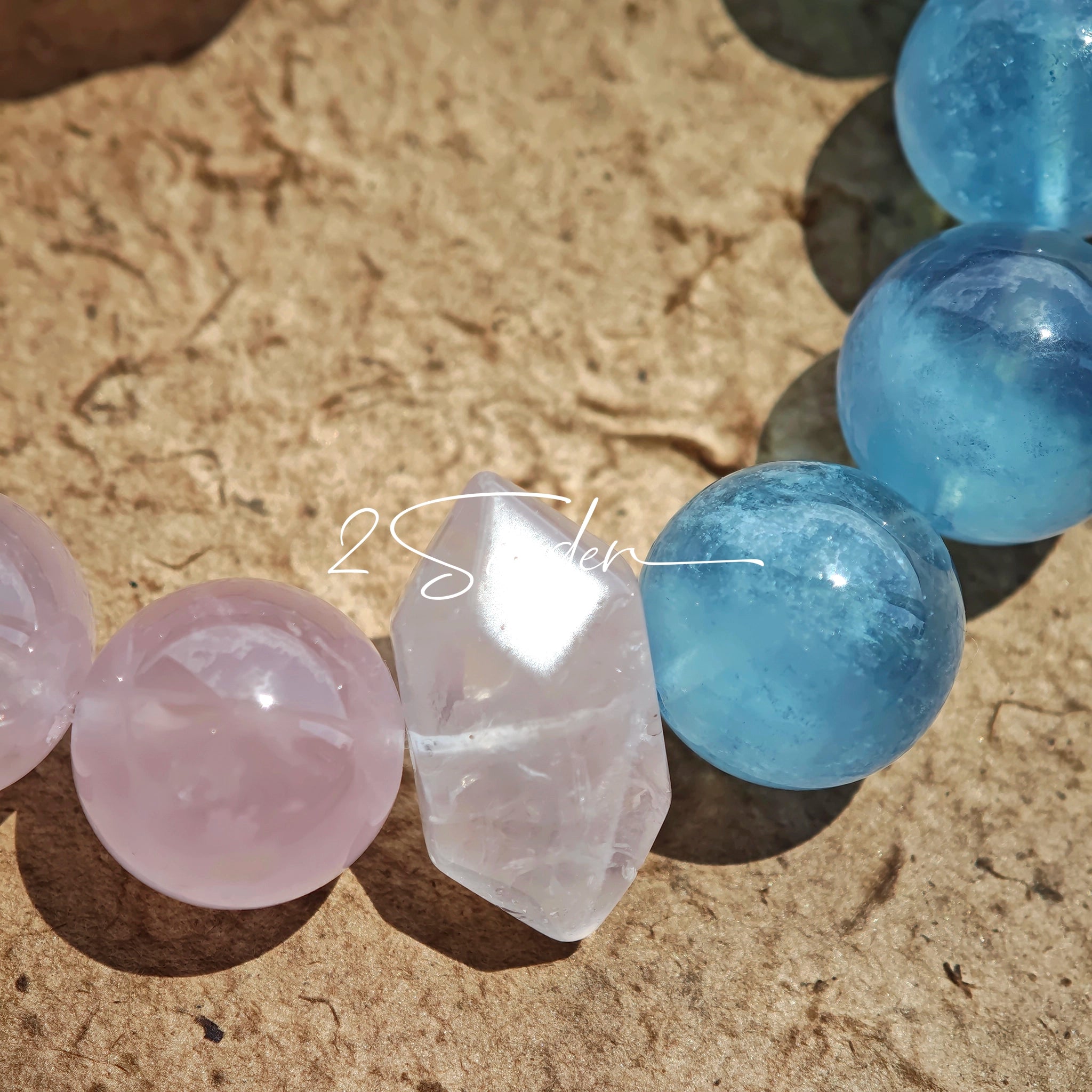 This bracelet consists of rose quartz and aquamarine. The bracelet features a bead pendant and a rhombic spacer, both of which are made of rose quartz. The bracelet is a combination of pink and blue colors.
