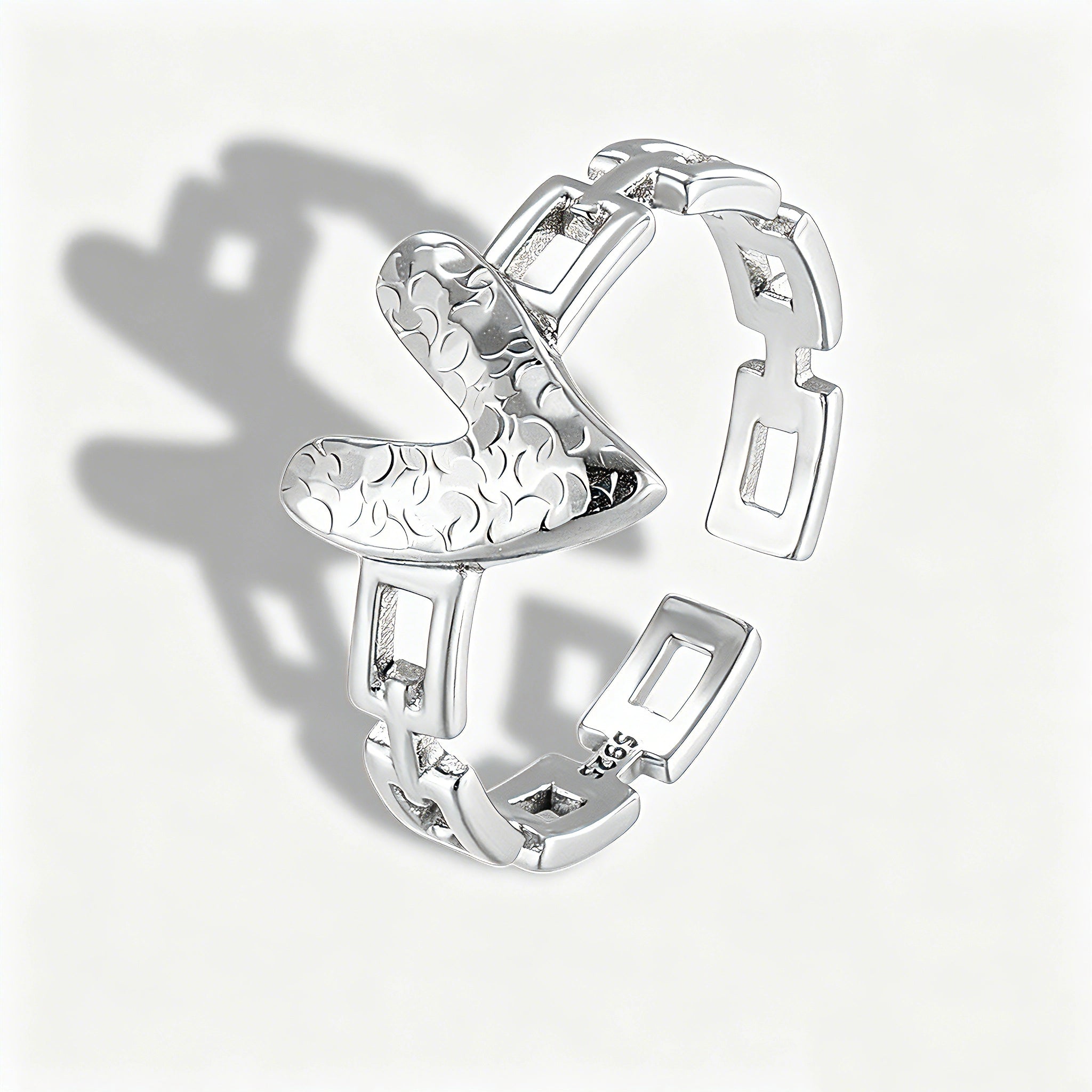 This is an adjustable open ring crafted from S925 sterling silver. It features a modern chain-link band paired with a textured heart-shaped centerpiece, boasting a "crushed ice" finish that delivers a sparkling, dimensional look. The polished silver tone lends a sleek, contemporary vibe to this versatile piece.