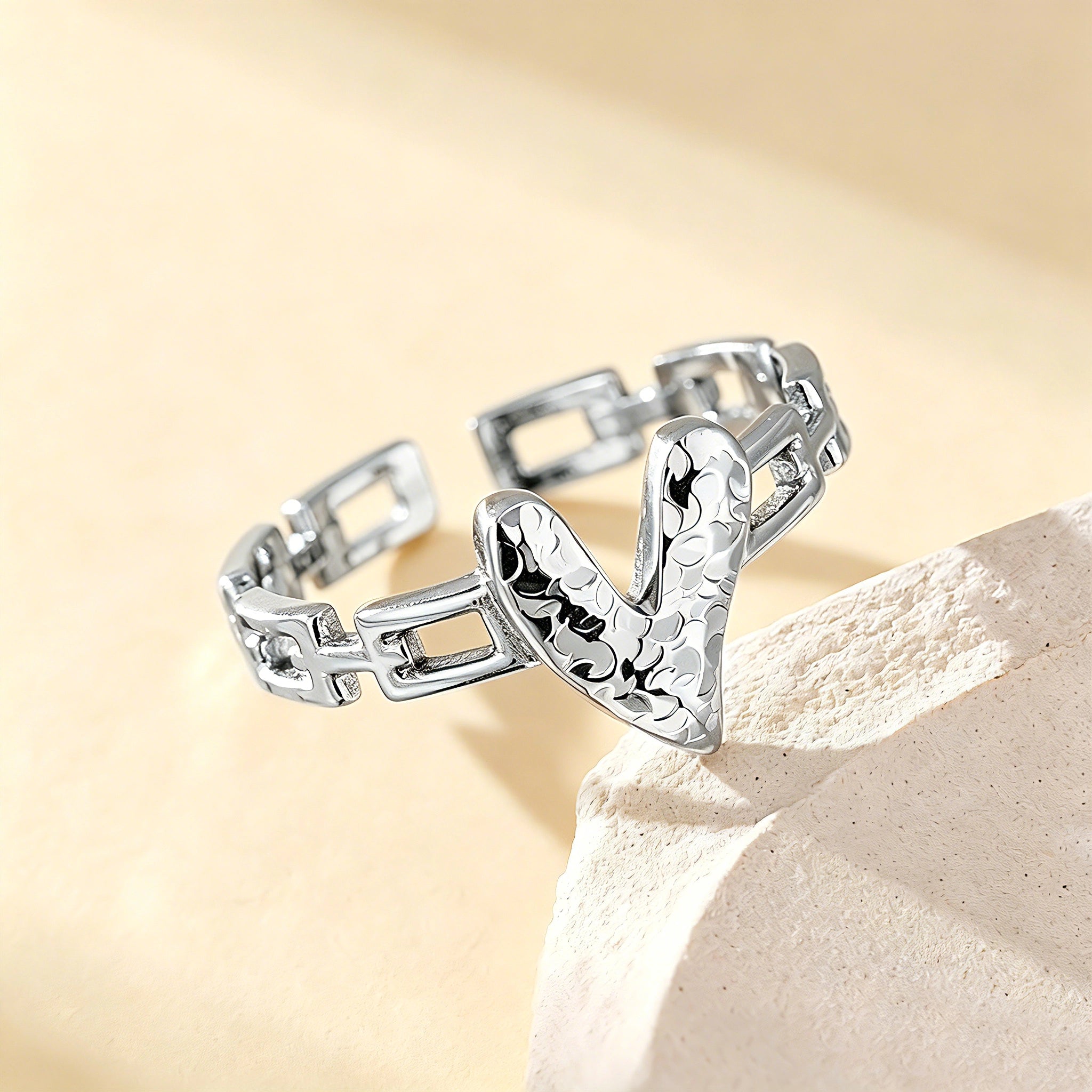 This is an adjustable open ring crafted from S925 sterling silver. It features a modern chain-link band paired with a textured heart-shaped centerpiece, boasting a "crushed ice" finish that delivers a sparkling, dimensional look. The polished silver tone lends a sleek, contemporary vibe to this versatile piece.