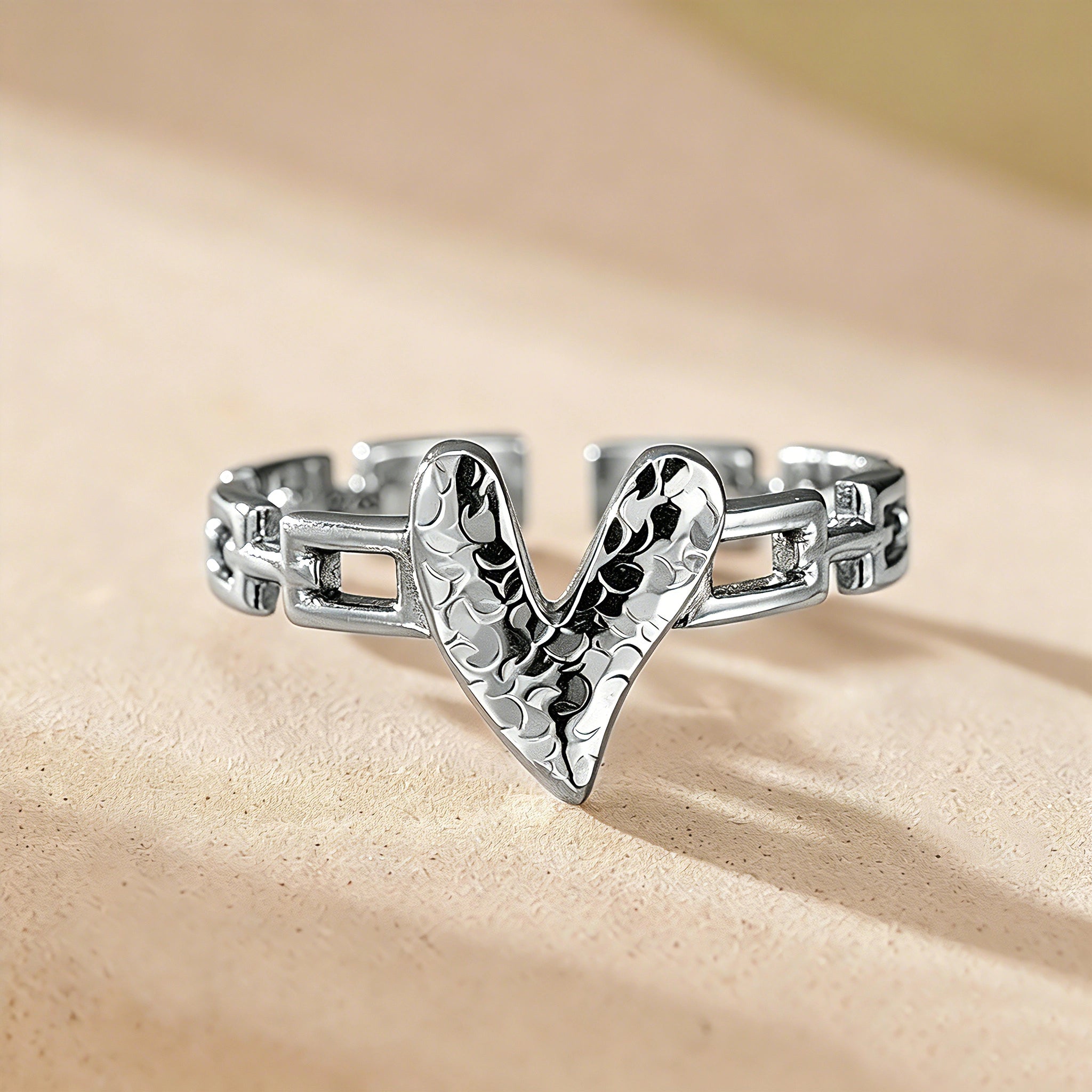 This is an adjustable open ring crafted from S925 sterling silver. It features a modern chain-link band paired with a textured heart-shaped centerpiece, boasting a "crushed ice" finish that delivers a sparkling, dimensional look. The polished silver tone lends a sleek, contemporary vibe to this versatile piece.