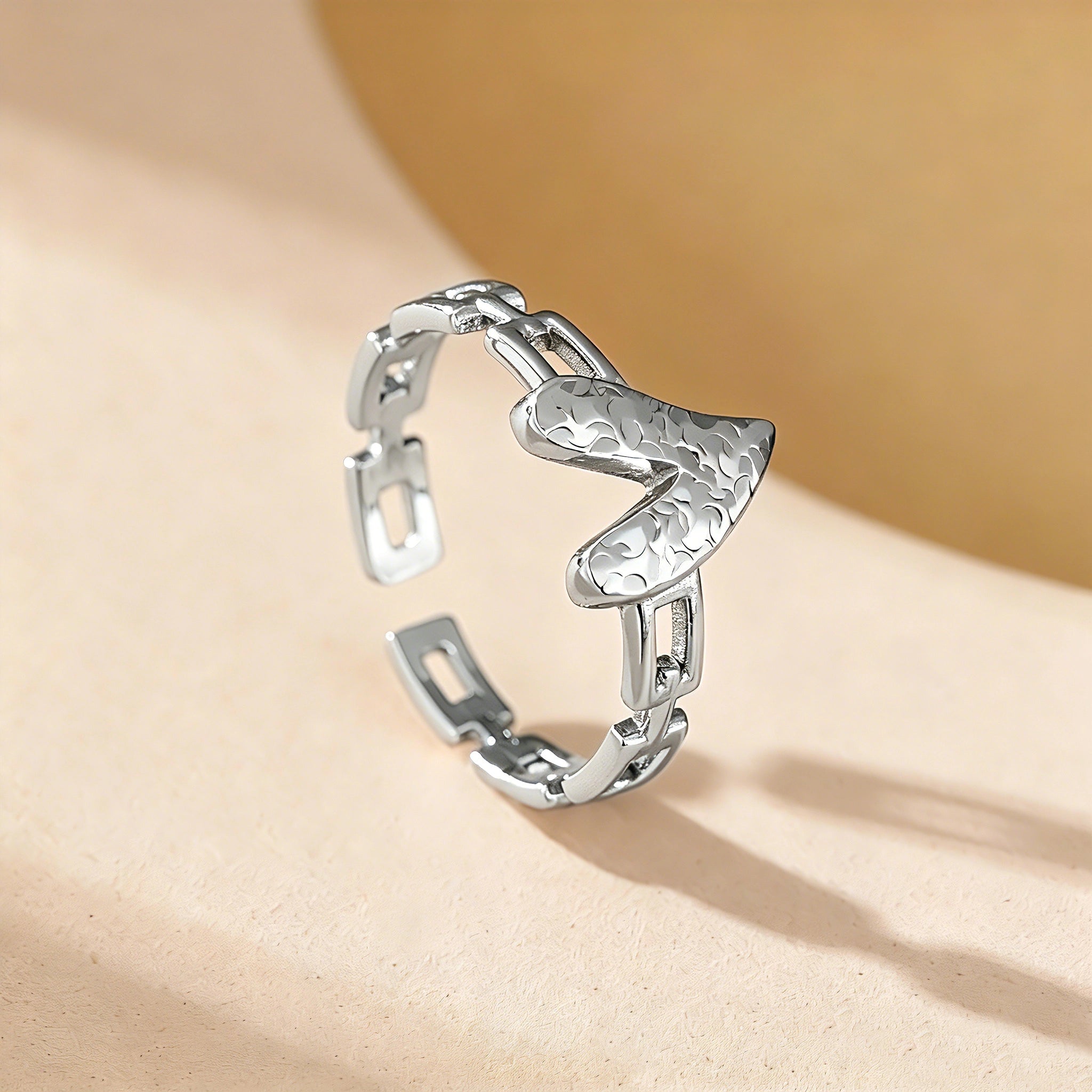 This is an adjustable open ring crafted from S925 sterling silver. It features a modern chain-link band paired with a textured heart-shaped centerpiece, boasting a "crushed ice" finish that delivers a sparkling, dimensional look. The polished silver tone lends a sleek, contemporary vibe to this versatile piece.