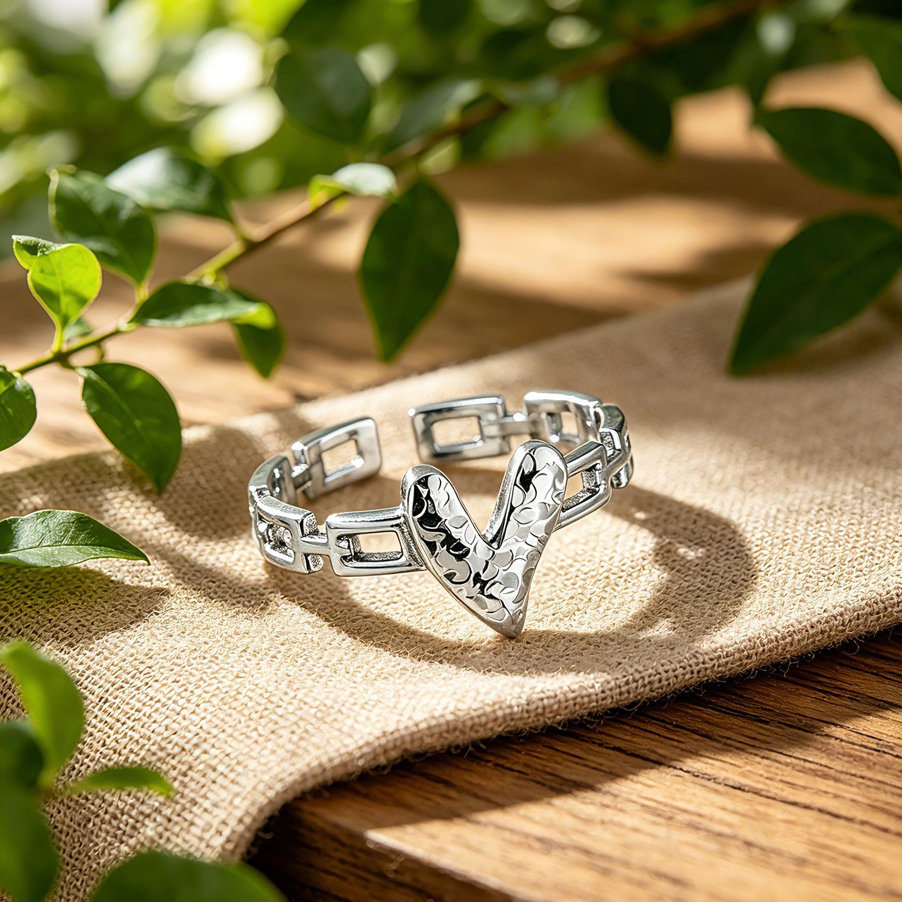 This is an adjustable open ring crafted from S925 sterling silver. It features a modern chain-link band paired with a textured heart-shaped centerpiece, boasting a "crushed ice" finish that delivers a sparkling, dimensional look. The polished silver tone lends a sleek, contemporary vibe to this versatile piece.