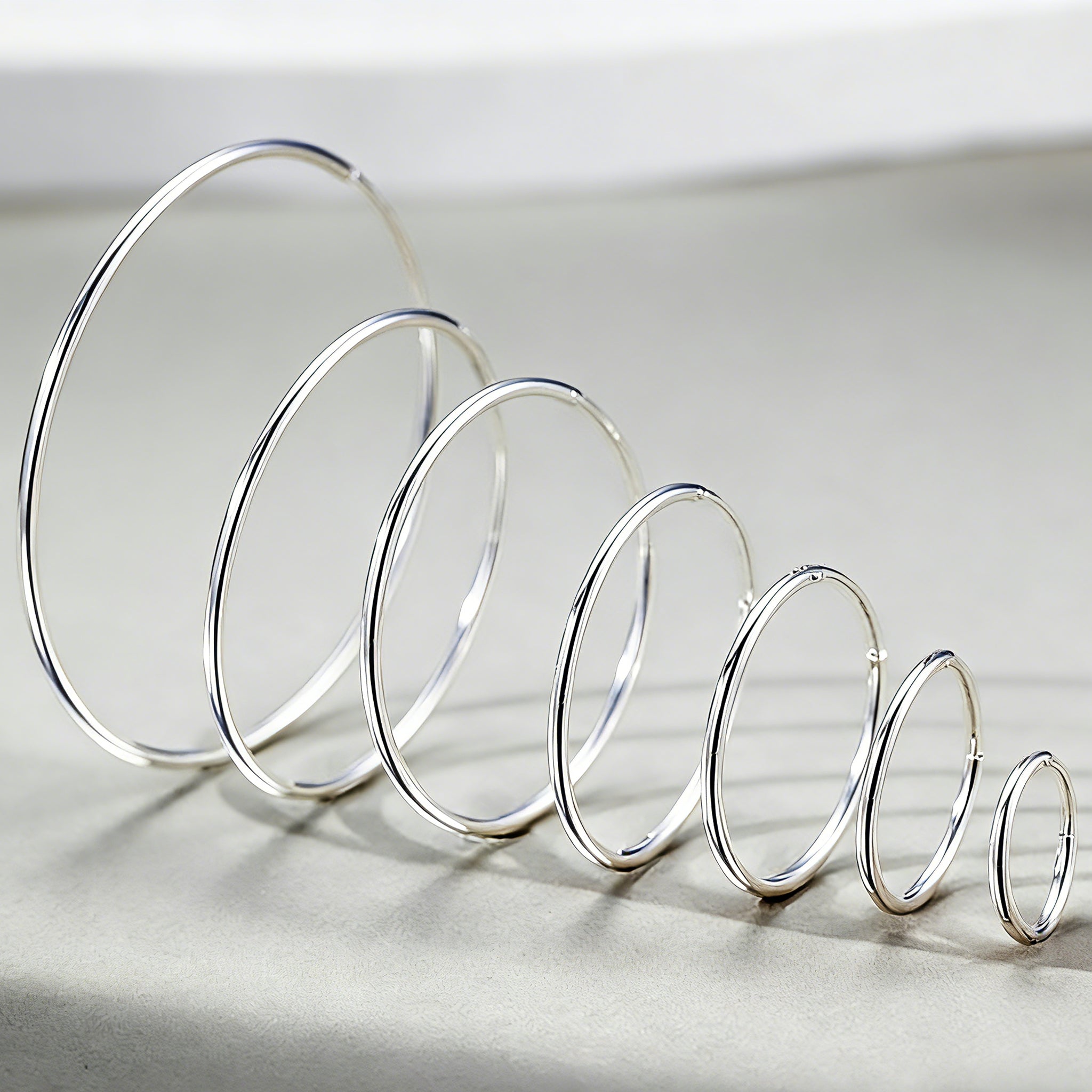 These S925 sterling silver hoop earrings feature a sleek, polished circular design with a smooth, reflective finish. They showcase a classic minimalist silhouette with a seamless, slender wire construction that exudes understated elegance. The polished surface catches light beautifully, highlighting their timeless and versatile appeal.