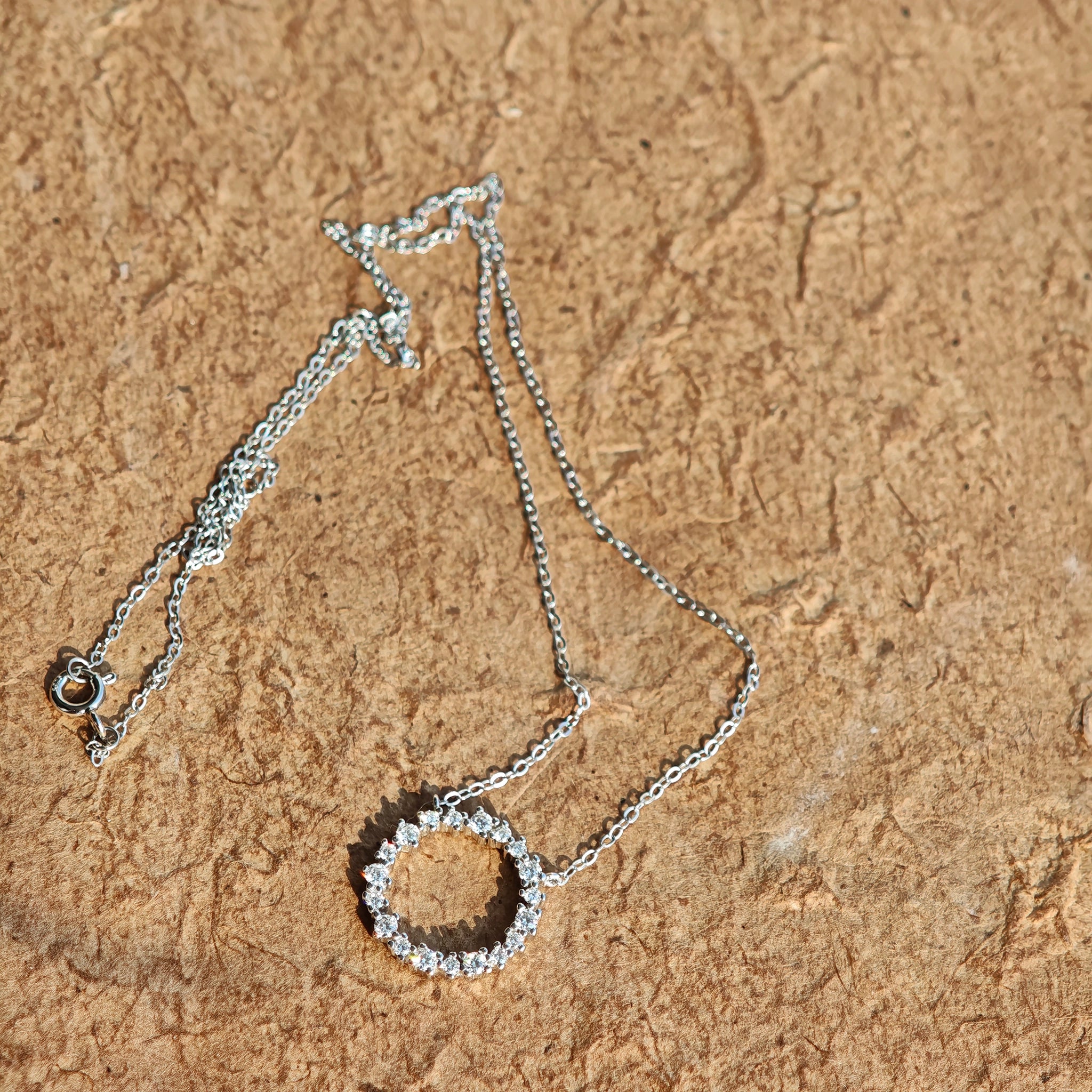 This S925 silver necklace features a delicate circular pendant encrusted with shimmering moissanite stones, forming an elegant open-circle silhouette. The slender silver chain complements the pendant perfectly, lending a refined and timeless charm to the piece. Its minimalist yet sparkling design makes it a versatile accessory for various occasions.