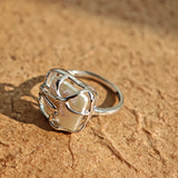 This adjustable S925 sterling silver ring features a striking baroque pearl at its center, set within an organic, flowing silver frame that wraps around the irregular, lustrous gemstone. The open, sculptural metalwork creates a modern, artistic silhouette, showcasing the pearl's natural, one-of-a-kind texture and soft iridescence. The sleek, polished silver band complements the unique pearl, making it a standout piece with a contemporary, bohemian aesthetic.