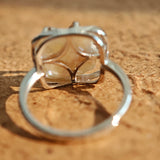This adjustable S925 sterling silver ring features a striking baroque pearl at its center, set within an organic, flowing silver frame that wraps around the irregular, lustrous gemstone. The open, sculptural metalwork creates a modern, artistic silhouette, showcasing the pearl's natural, one-of-a-kind texture and soft iridescence. The sleek, polished silver band complements the unique pearl, making it a standout piece with a contemporary, bohemian aesthetic.